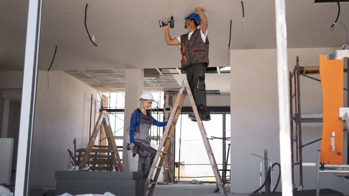 deux personnes équipées, rénovant l'intérieur d'une maison. 